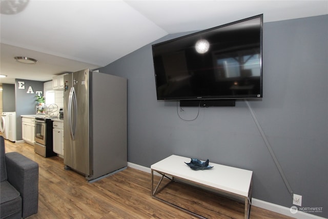 living room featuring washer and clothes dryer, lofted ceiling, and wood-type flooring