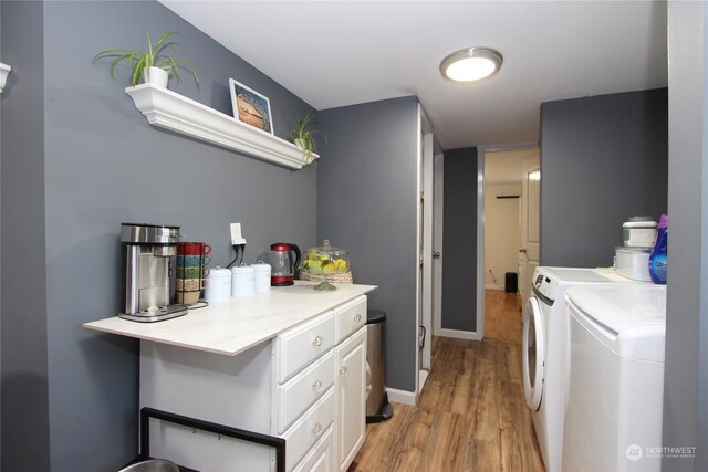 laundry area featuring cabinets, light hardwood / wood-style floors, and separate washer and dryer