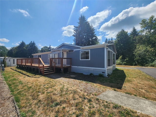 rear view of house featuring a wooden deck and a lawn