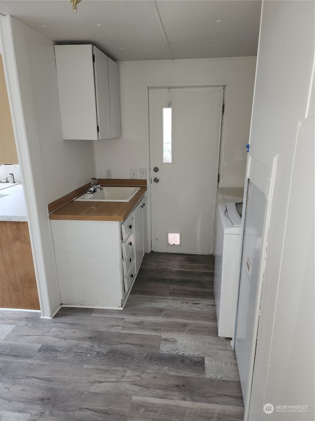 kitchen featuring white cabinetry, light hardwood / wood-style floors, washer / clothes dryer, and sink