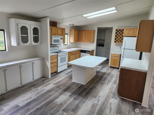 kitchen featuring white appliances, lofted ceiling, a center island, hardwood / wood-style flooring, and sink