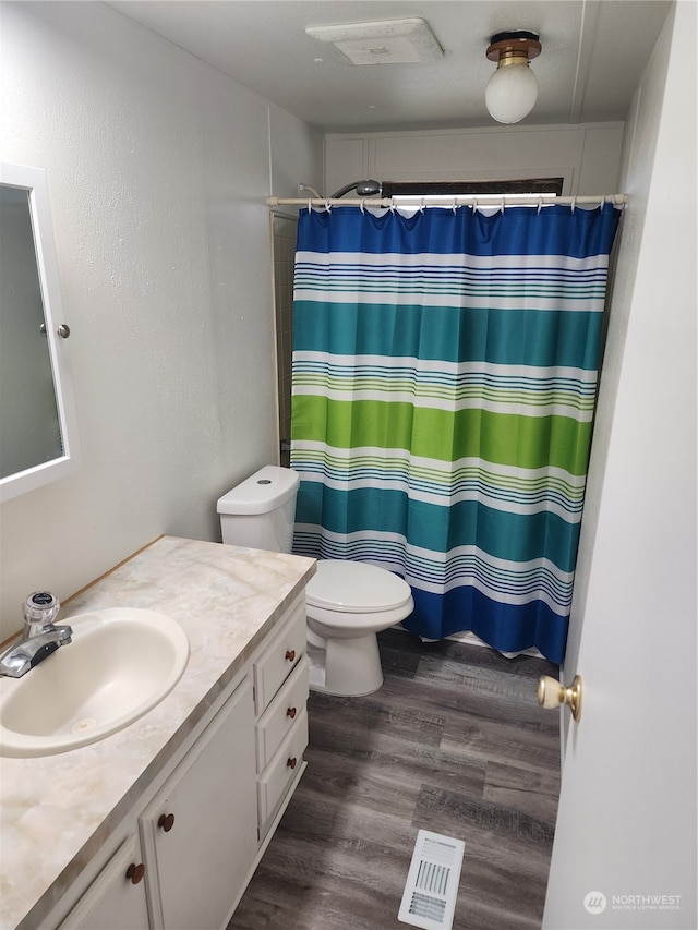 bathroom featuring a shower with shower curtain, hardwood / wood-style floors, vanity, and toilet