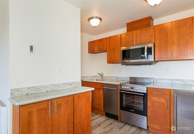 kitchen with light stone counters, wine cooler, sink, stainless steel appliances, and light wood-type flooring