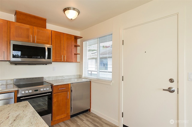 kitchen with appliances with stainless steel finishes, light hardwood / wood-style flooring, and light stone counters