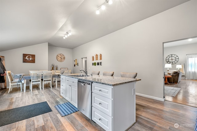 kitchen featuring light hardwood / wood-style floors, vaulted ceiling, stainless steel dishwasher, and a center island with sink