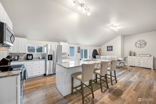 kitchen featuring stainless steel appliances, a kitchen island, a kitchen breakfast bar, and white cabinets