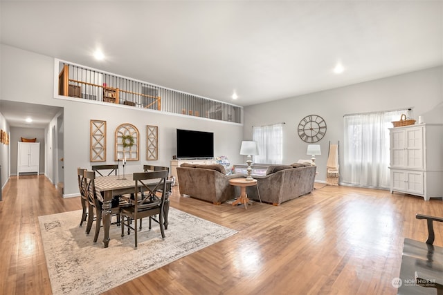 dining area featuring light hardwood / wood-style flooring and a towering ceiling