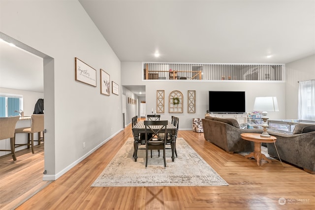 dining room featuring a towering ceiling and light wood-type flooring