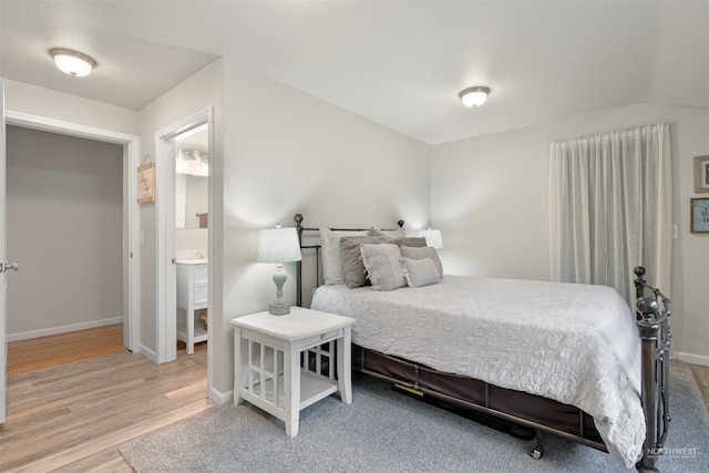 bedroom with ensuite bathroom and light hardwood / wood-style floors