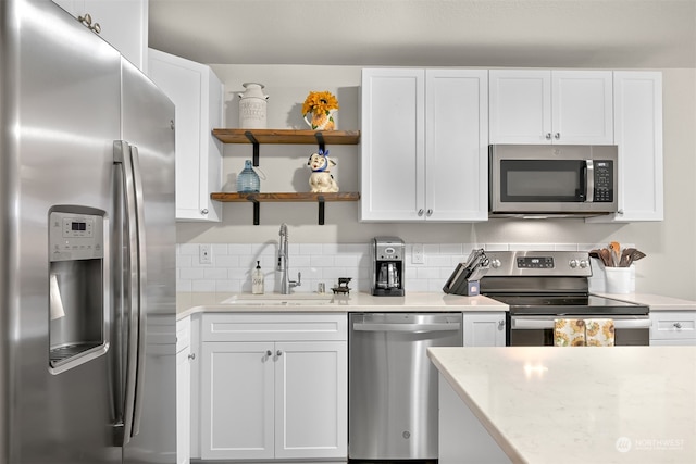 kitchen featuring light stone countertops, appliances with stainless steel finishes, sink, white cabinetry, and decorative backsplash