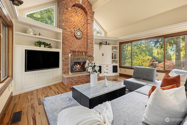 living room featuring light hardwood / wood-style flooring, a fireplace, high vaulted ceiling, and a wealth of natural light