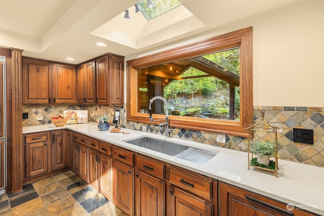 kitchen with backsplash, a skylight, a tray ceiling, and sink