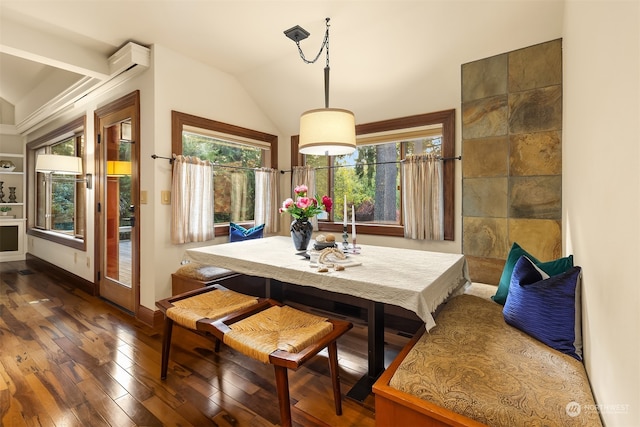 dining area featuring vaulted ceiling, a wall mounted air conditioner, plenty of natural light, and dark hardwood / wood-style flooring