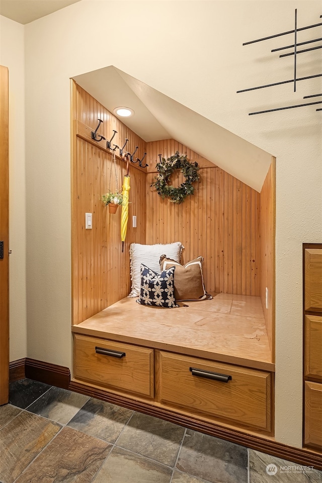 mudroom with wooden walls and vaulted ceiling