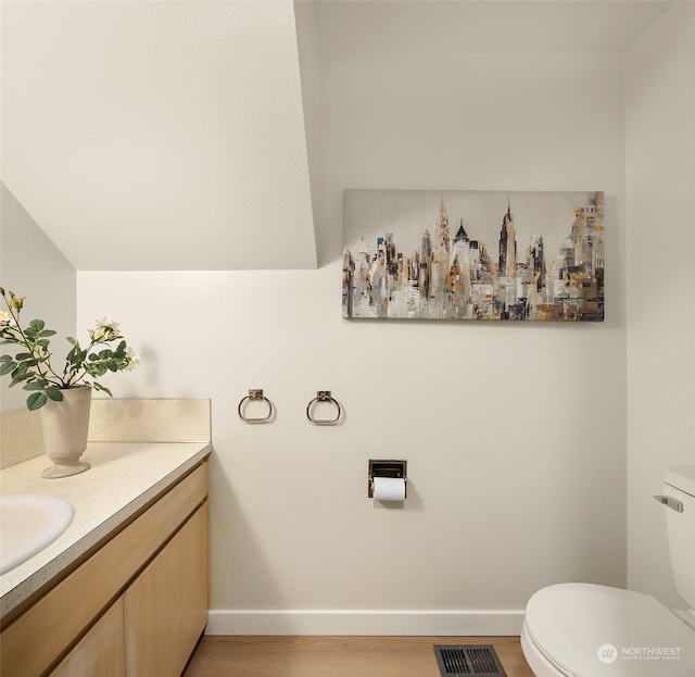 bathroom with hardwood / wood-style floors, vanity, and toilet