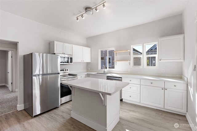 kitchen with a kitchen island, white cabinets, sink, light hardwood / wood-style floors, and appliances with stainless steel finishes