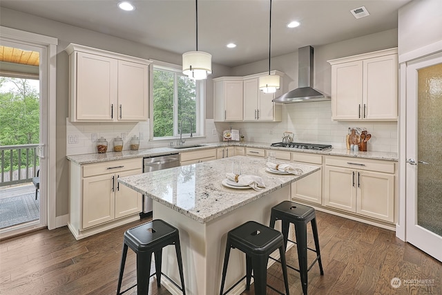 kitchen featuring wall chimney exhaust hood, a kitchen island, sink, and plenty of natural light