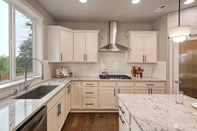 kitchen with dark hardwood / wood-style floors, sink, wall chimney exhaust hood, decorative light fixtures, and light stone countertops