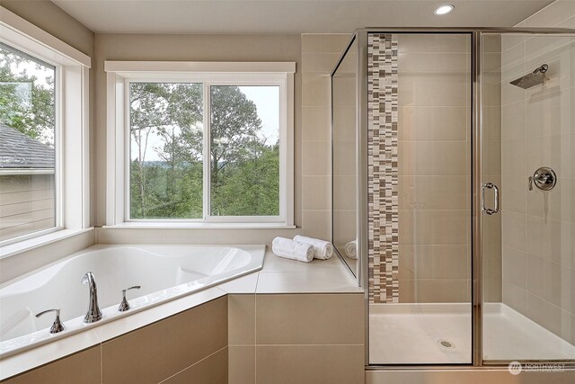 bathroom with shower with separate bathtub and plenty of natural light