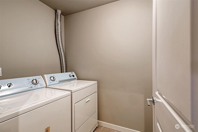 clothes washing area featuring light tile patterned floors and washer and clothes dryer