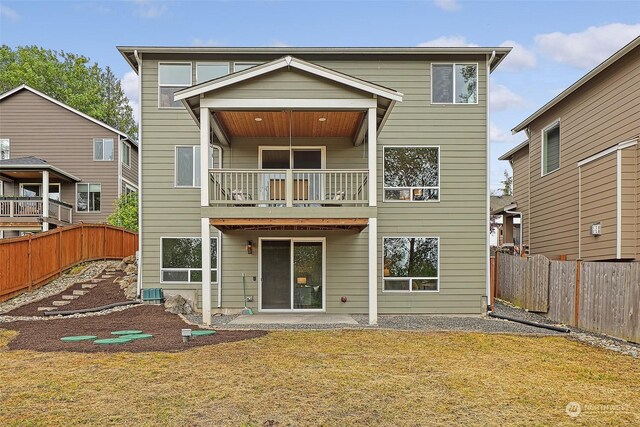 back of house with central AC unit, a balcony, a lawn, and a patio