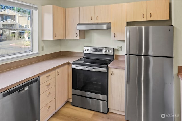 kitchen with ventilation hood, light brown cabinetry, stainless steel appliances, and light hardwood / wood-style floors