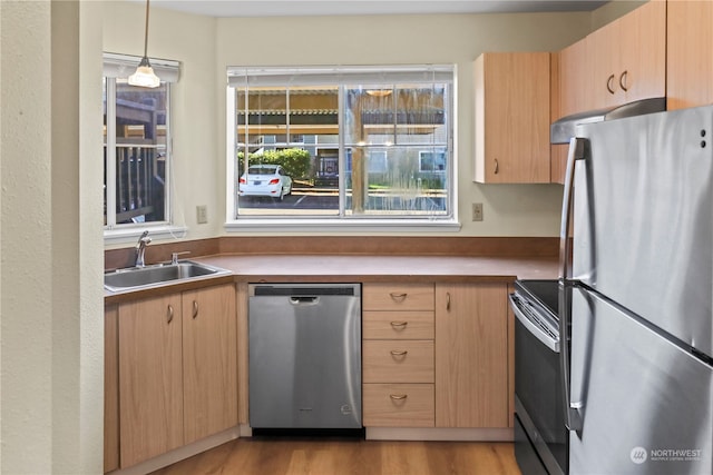 kitchen featuring sink, decorative light fixtures, light hardwood / wood-style flooring, appliances with stainless steel finishes, and light brown cabinetry