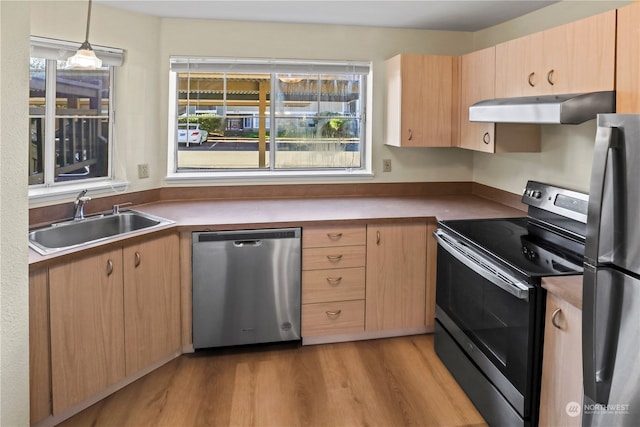 kitchen featuring light hardwood / wood-style floors, sink, hanging light fixtures, stainless steel appliances, and extractor fan