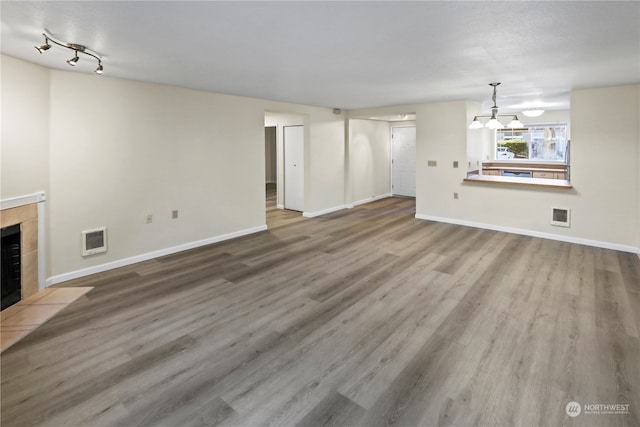 unfurnished living room featuring a tile fireplace, wood-type flooring, and a notable chandelier