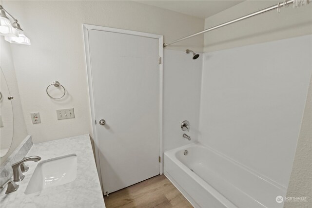 bathroom with vanity, hardwood / wood-style flooring, and washtub / shower combination