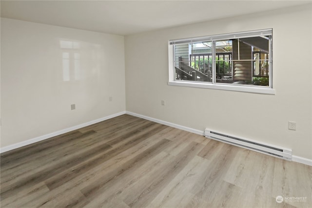 empty room featuring a baseboard heating unit and hardwood / wood-style flooring