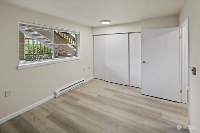 unfurnished bedroom with light hardwood / wood-style floors, a closet, and a baseboard radiator