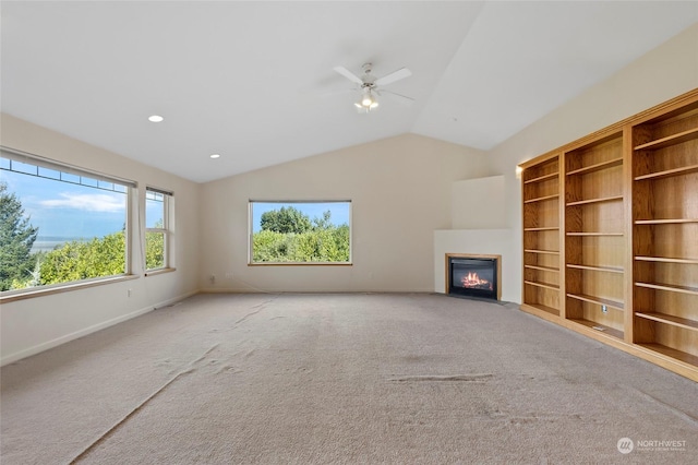 unfurnished living room with baseboards, a ceiling fan, carpet floors, vaulted ceiling, and a fireplace with flush hearth