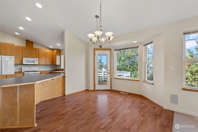 kitchen with light wood-style floors, pendant lighting, white appliances, vaulted ceiling, and a chandelier