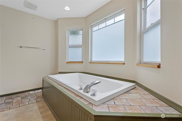 bathroom featuring a garden tub, stone finish floor, baseboards, and recessed lighting