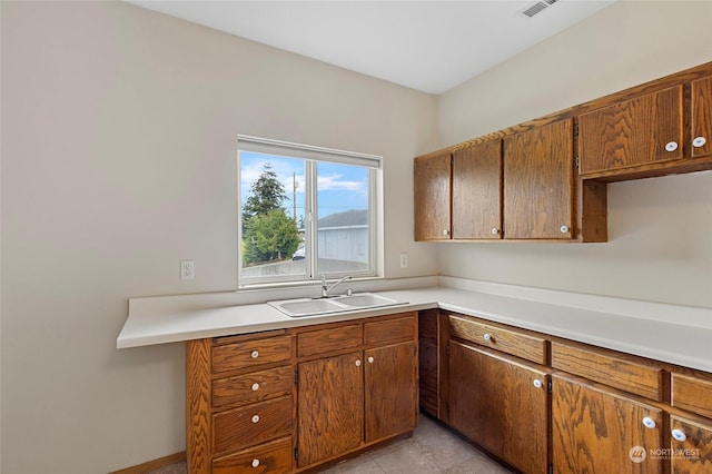 kitchen featuring light countertops, a sink, and brown cabinetry