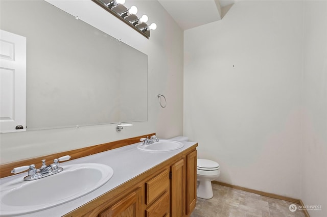 bathroom featuring double vanity, baseboards, a sink, and toilet