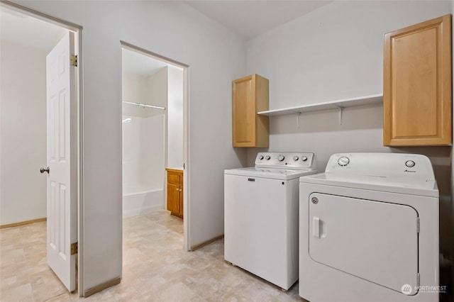 clothes washing area featuring cabinet space, baseboards, and separate washer and dryer