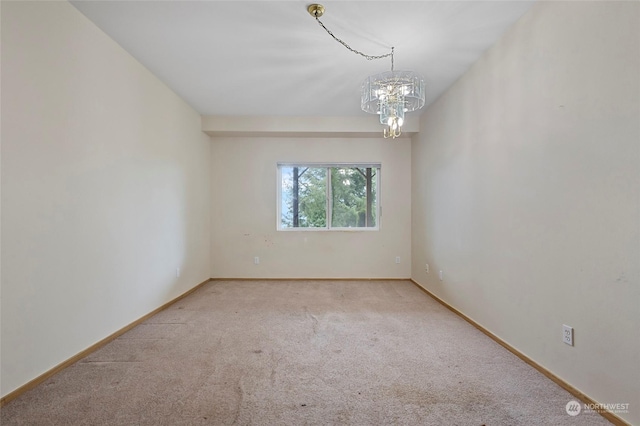 spare room featuring baseboards, carpet flooring, and a notable chandelier