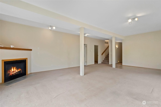 finished below grade area with a fireplace with flush hearth, carpet, and stairs