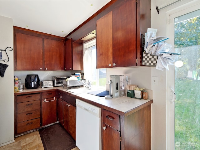 kitchen featuring white dishwasher, tile counters, and sink