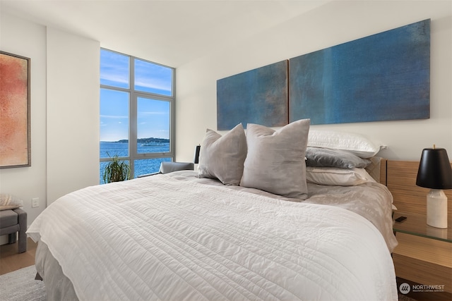 bedroom featuring floor to ceiling windows, a water view, and hardwood / wood-style floors