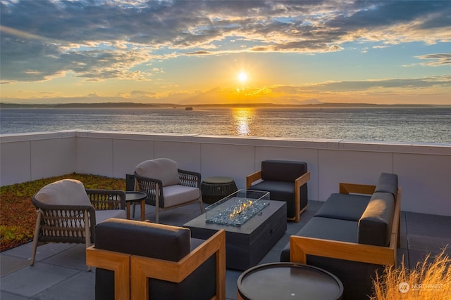 patio terrace at dusk with an outdoor living space with a fire pit and a water view