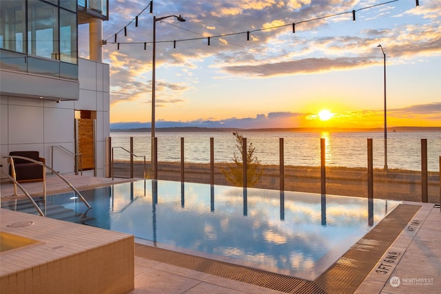 pool at dusk featuring a water view