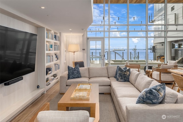 living room featuring floor to ceiling windows, a water view, hardwood / wood-style floors, and built in shelves