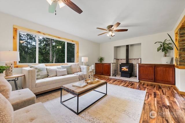 living room with a wood stove, ceiling fan, and hardwood / wood-style flooring