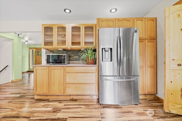 kitchen with light brown cabinetry, stainless steel appliances, light wood-type flooring, and decorative backsplash