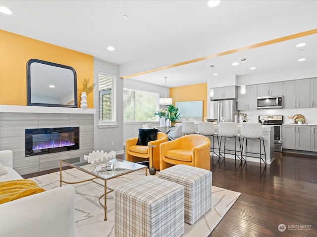 living room with dark wood-type flooring and a tile fireplace