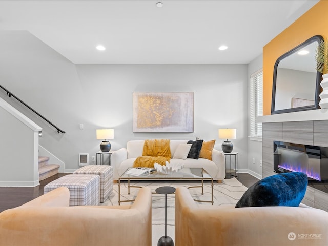 living room with a tile fireplace and hardwood / wood-style flooring