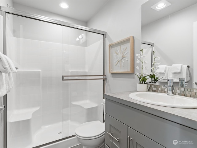 bathroom featuring vanity, toilet, and a shower with door